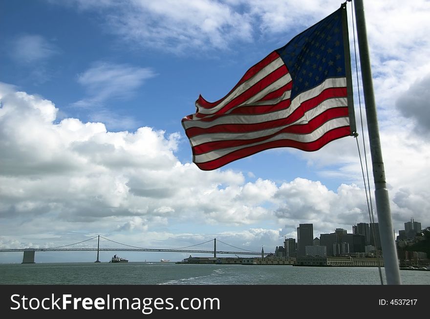 American flag flutters in wind of a tourist boat heading away from San Francisco towards alcatraz.