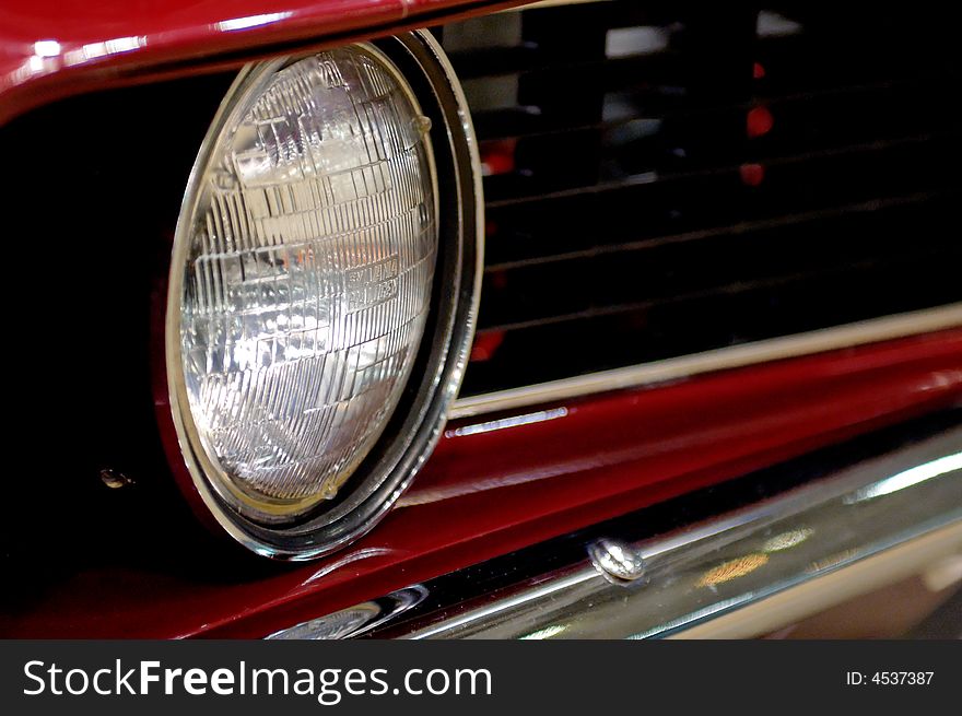 Red automobile body with black grille and chrome headlamp. Red automobile body with black grille and chrome headlamp.