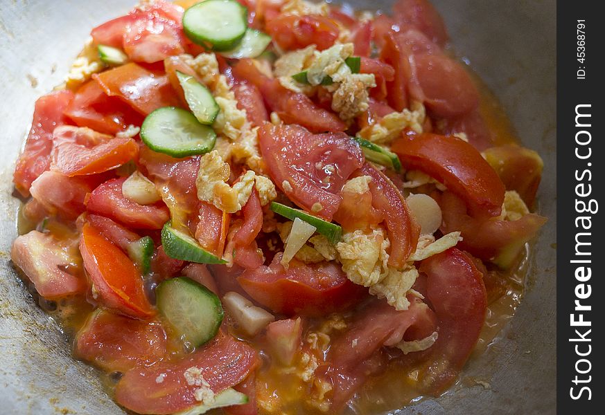 Close-up of home cooking of tomato cucumber and eggs cooking together in the wok. Close-up of home cooking of tomato cucumber and eggs cooking together in the wok