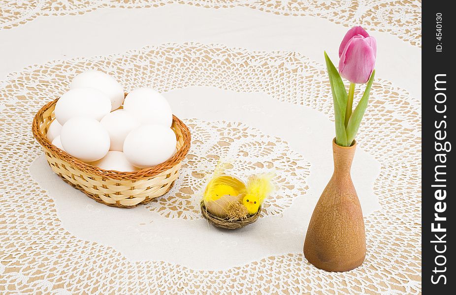 A basket of eggs, easter chicken and a pink tulip