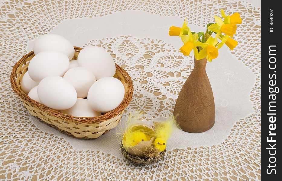 A basket of eggs, easter chicken and yellow daffodils