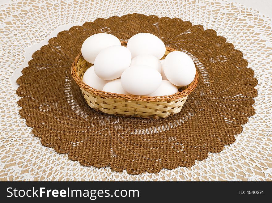 A basket of white eggs on the brown tablecloth. A basket of white eggs on the brown tablecloth