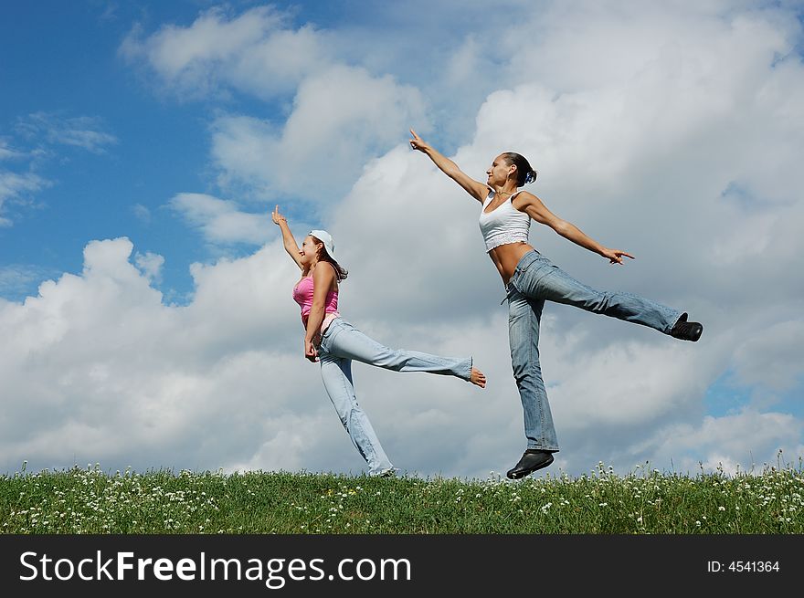 Jumping girls on the green meadow