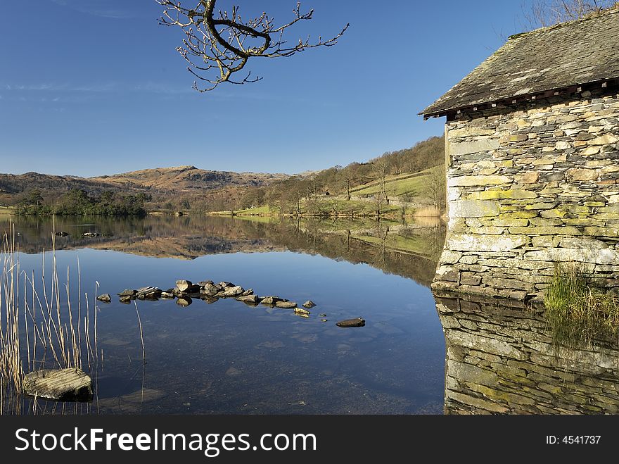 A boathouse reflected in the still waters of Rydal Water in the English Lake District. A boathouse reflected in the still waters of Rydal Water in the English Lake District.