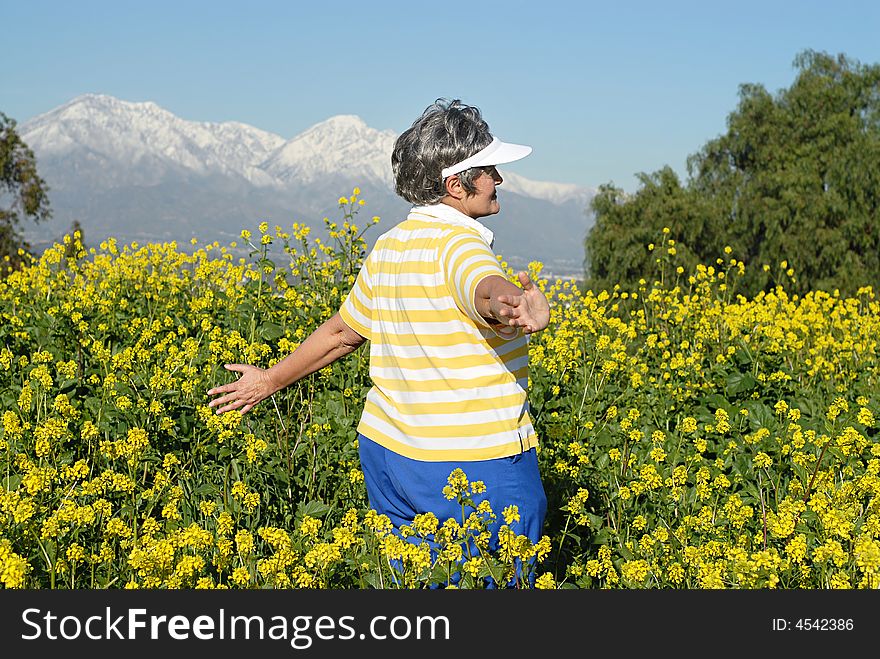 Senior woman walking through a meadow with open arms. Senior woman walking through a meadow with open arms