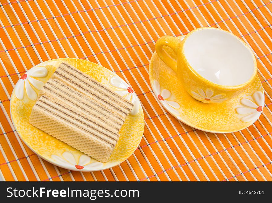 Close-up waffle slice and empty cup on bamboo table-cloth