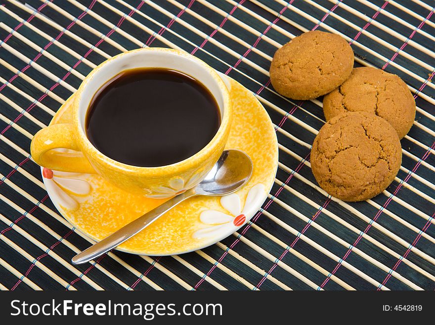 Cookies and cup with coffee on bamboo table-cloth