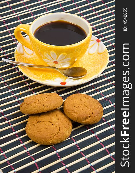 Close-up cookies and cup with coffee on bamboo table-cloth