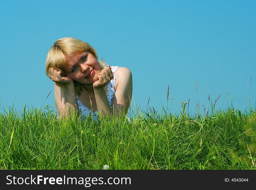 Woman lie on green grass under blue sky