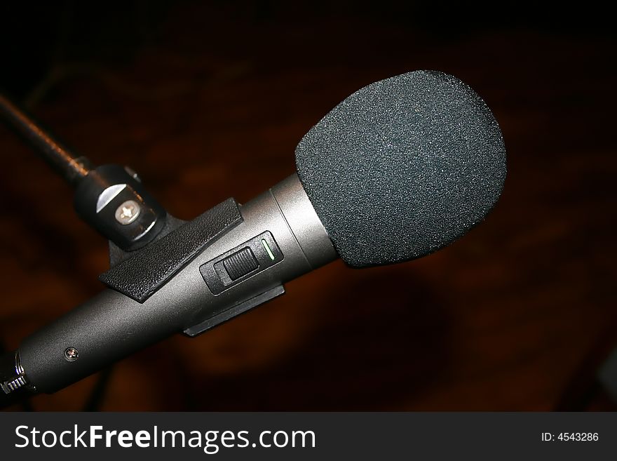 Gray microphone on stand, brown background