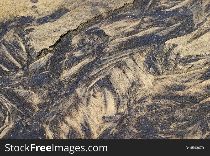 Dark sand makes patterrns on lighter sand in the bed of a rivulet. Mica grains reflect tiny spots of sunlight like mirrors. Dark sand makes patterrns on lighter sand in the bed of a rivulet. Mica grains reflect tiny spots of sunlight like mirrors.