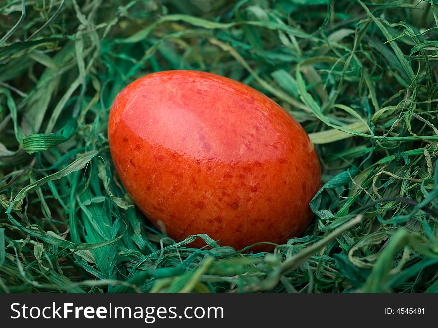 Red easter egg on the green hay. Selective focus, shallow depth of field. Red easter egg on the green hay. Selective focus, shallow depth of field.