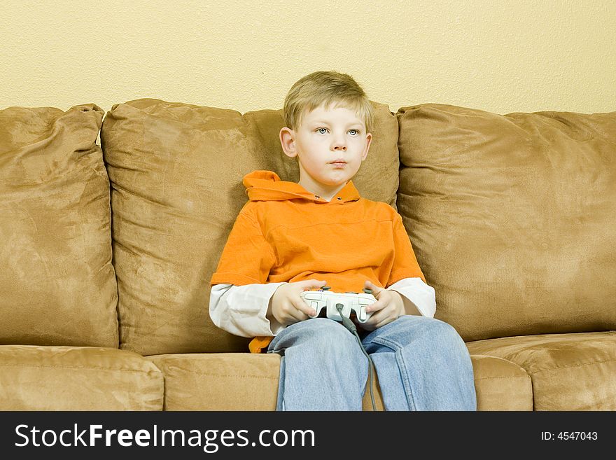 Young boy sitting on couch playing a game. Young boy sitting on couch playing a game