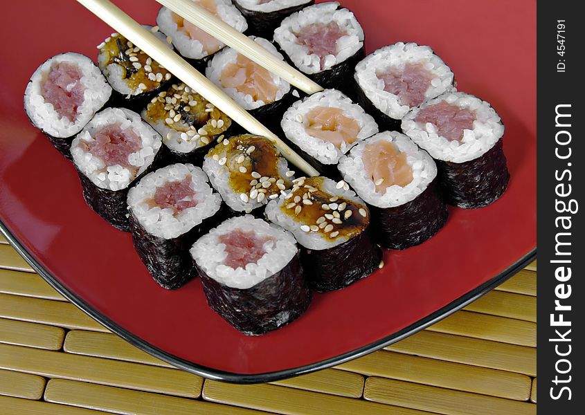 Different types of sushi with chopsticks on an Asian plate. Different types of sushi with chopsticks on an Asian plate.