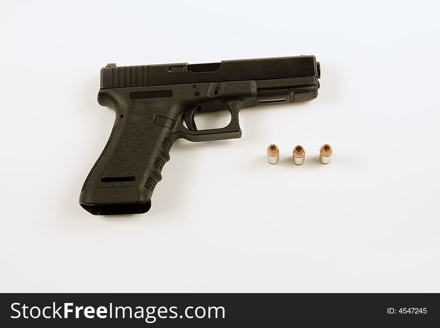 Picture of a 40mm handgun isolated on white with several hollowpoint bullets next to it.