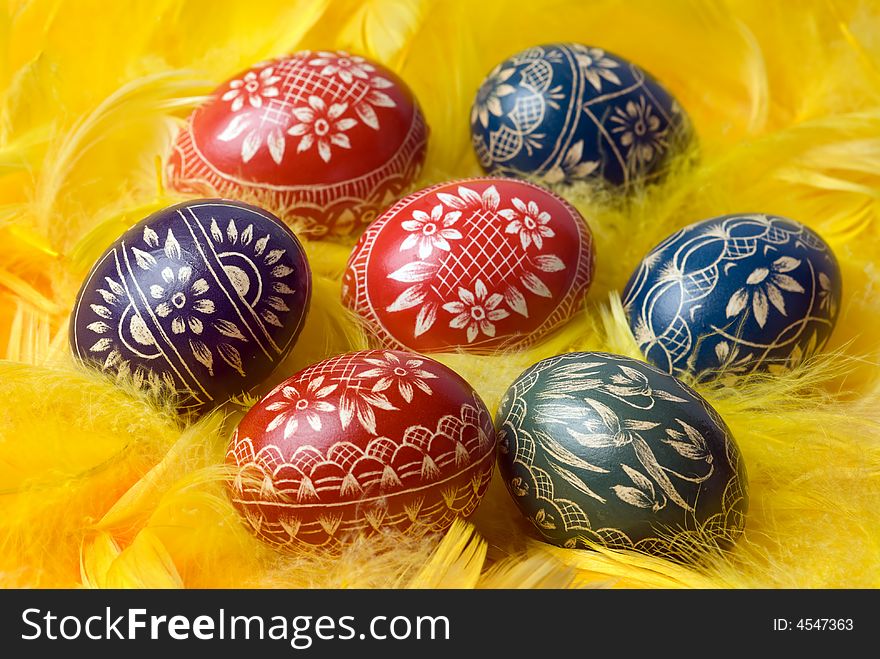 Handmade easter eggs on yellow feathers. Selective focus, shallow depth of field. Handmade easter eggs on yellow feathers. Selective focus, shallow depth of field.