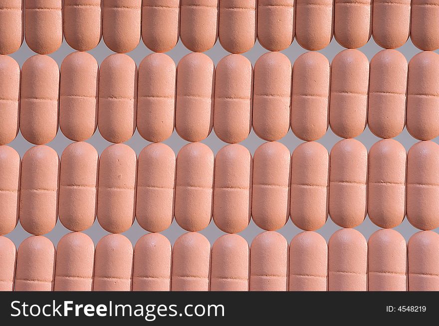 Rows of pink pills over grey. Macro. Close-up