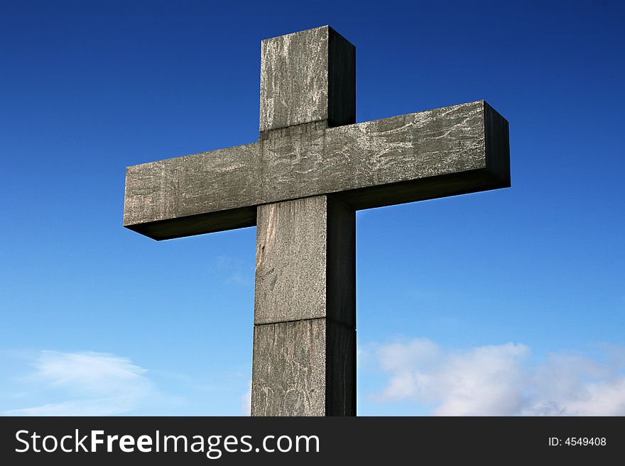 A old stone cross under a blue sky.