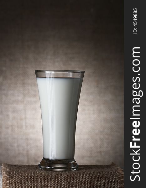 Single Glass of Milk on burlap canvas and brown rustic background, Low Key  Lighting Technique