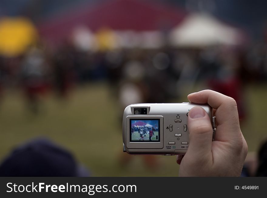 Man's hand with small digital point&shot camera on the open air event. Man's hand with small digital point&shot camera on the open air event