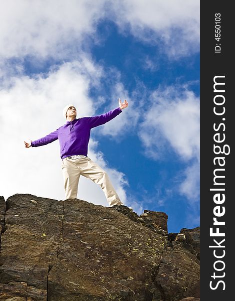 Young man on the rocks in defiant gesture. Young man on the rocks in defiant gesture