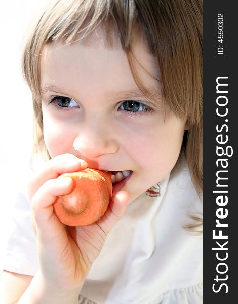 Happy little girl bites fresh carrot in the sunlight. Happy little girl bites fresh carrot in the sunlight