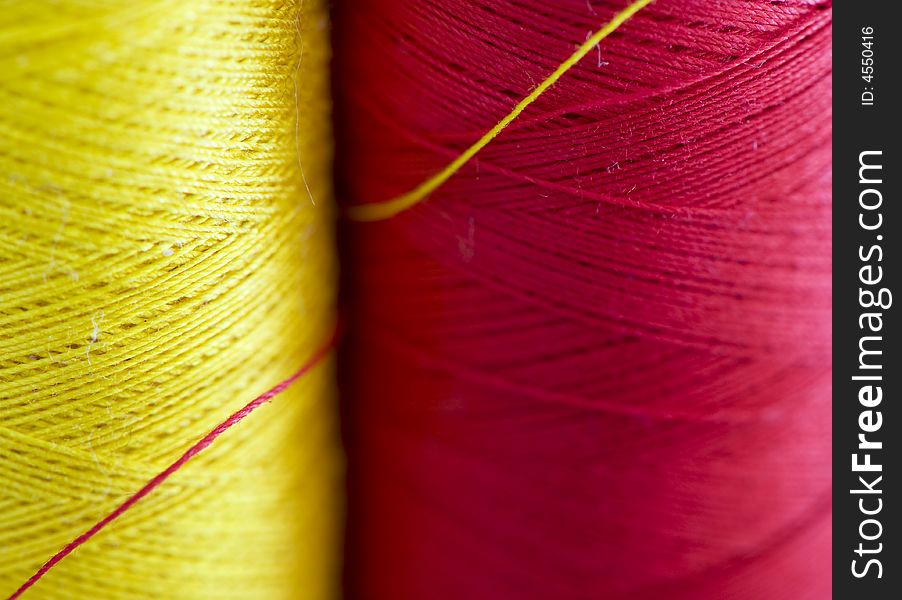 Spools of red and yellow thread close up.