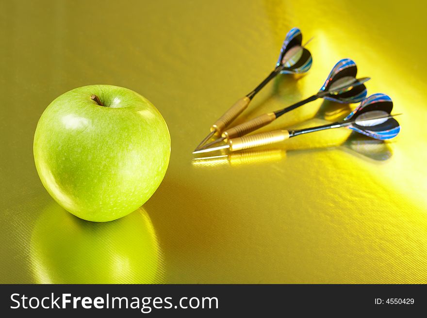 Apple and the three darts laying on a golden background. Apple and the three darts laying on a golden background