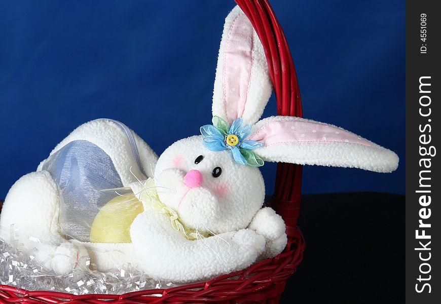 Rabbit with easter eggs standing in basket over dark blue background. Rabbit with easter eggs standing in basket over dark blue background