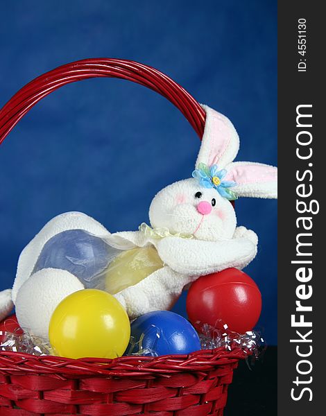 Rabbit with easter eggs standing in basket over blue background. Rabbit with easter eggs standing in basket over blue background