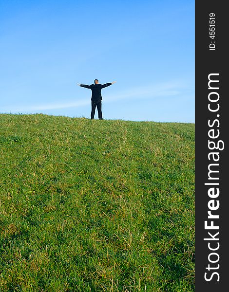 The businessman on a hill extended upwards hands
