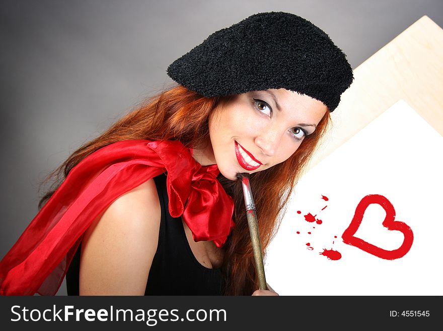 Beautiful artist is painting red heart