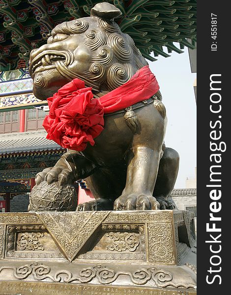 A golden lion sulpture in front of a ancient temple.Xian,China. A golden lion sulpture in front of a ancient temple.Xian,China.