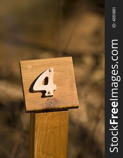 A mile marker on a woodland trail showing number four. A mile marker on a woodland trail showing number four