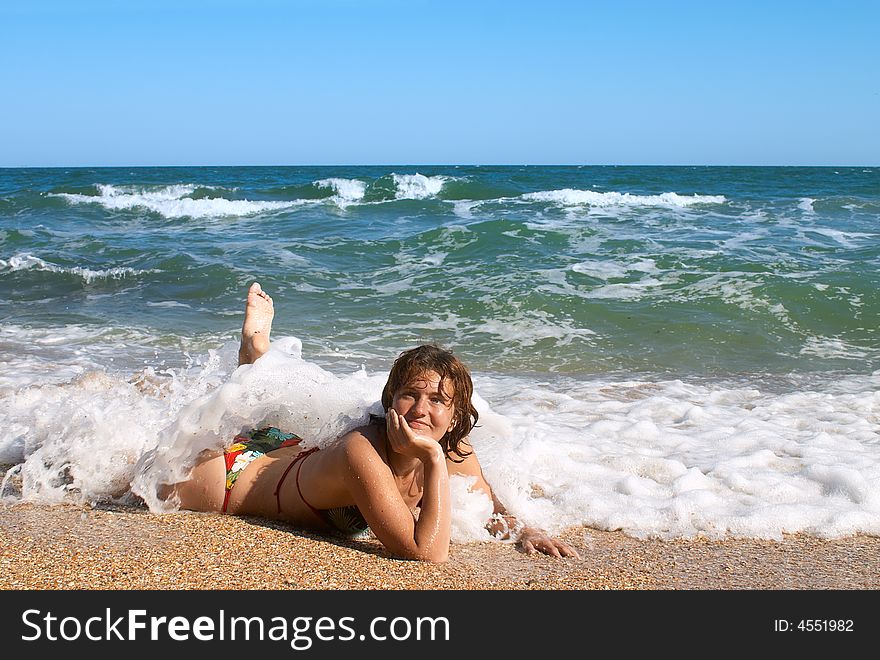 Girl in bikini sunburning in the waves on sand beach. Girl in bikini sunburning in the waves on sand beach