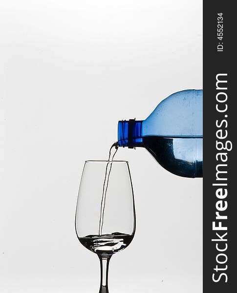 Pouring water into a wine glass from a blue bottle