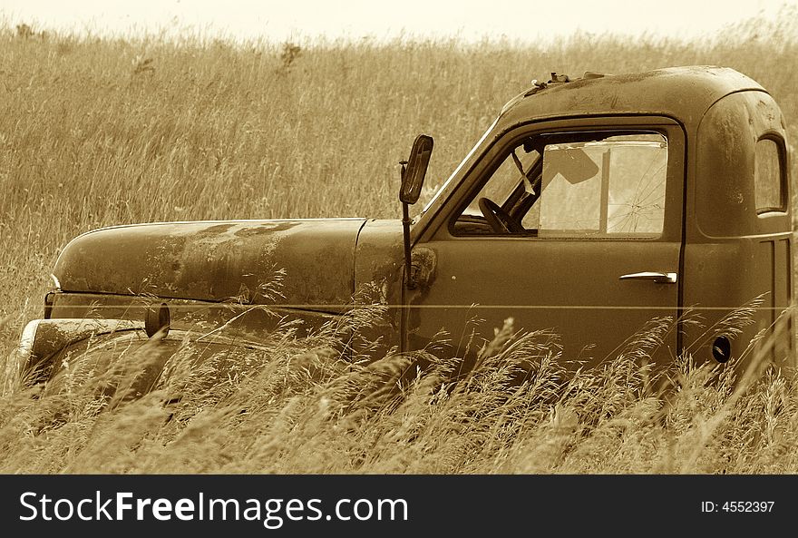 This is a photo of a worn, abandoned truck in a open field of weeds. This is a photo of a worn, abandoned truck in a open field of weeds.