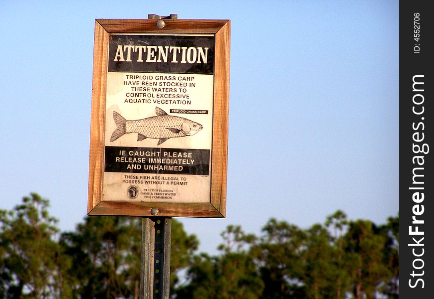 Grass Carp sign stating they are stocked and protected in this pond to control excessive aquatic vegetation