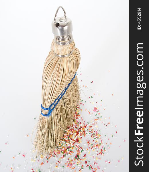 Small hand broom from above with litter of sprinkles on the ground. Small hand broom from above with litter of sprinkles on the ground.