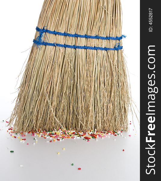 Small straw hand broom sweeping up sprinkles off floor. Small straw hand broom sweeping up sprinkles off floor.