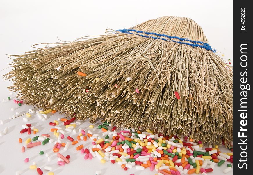 Small straw hand broom on it's side with sprinkle debris inside it's thistles. Small straw hand broom on it's side with sprinkle debris inside it's thistles.