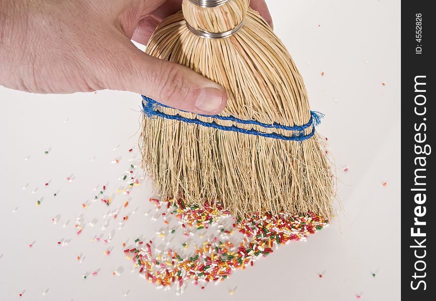 Hand sweeping sprinkles with a straw hand broom.  Photographed from a hign angle.