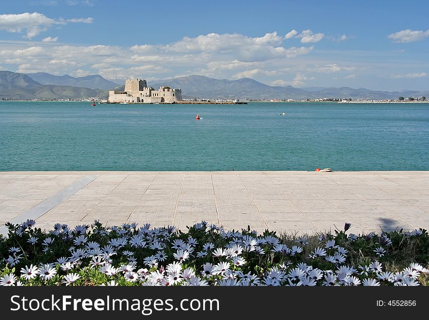 The castle island of Bourtzi, in Nafplio (Greece), with daisies in the foreground. The castle island of Bourtzi, in Nafplio (Greece), with daisies in the foreground