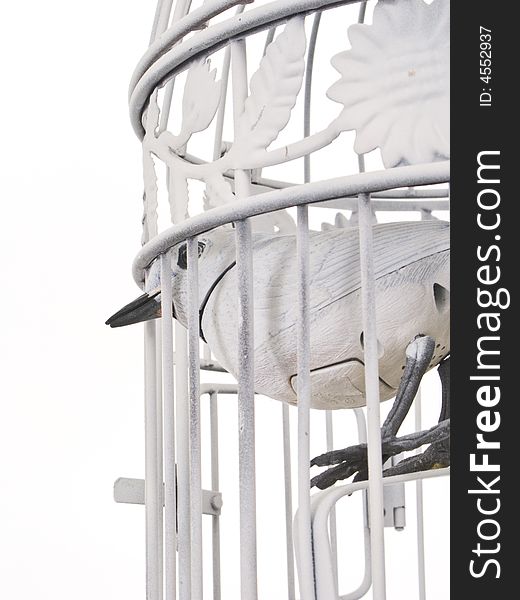 White bird cage with a white mechanical bird looking out of it's bars. Camera angle is from below and slightly from behind. White bird cage with a white mechanical bird looking out of it's bars. Camera angle is from below and slightly from behind.