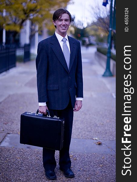 Young businessman standing holding briefcase looking at camera. Young businessman standing holding briefcase looking at camera