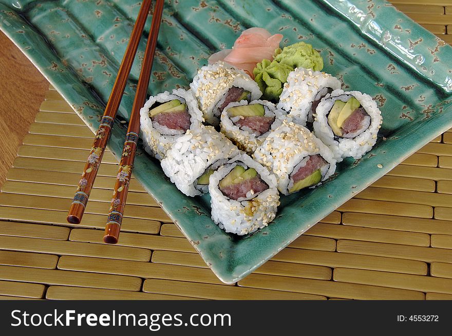 Different types of sushi rolls with chopsticks on an Asian plate. Different types of sushi rolls with chopsticks on an Asian plate.