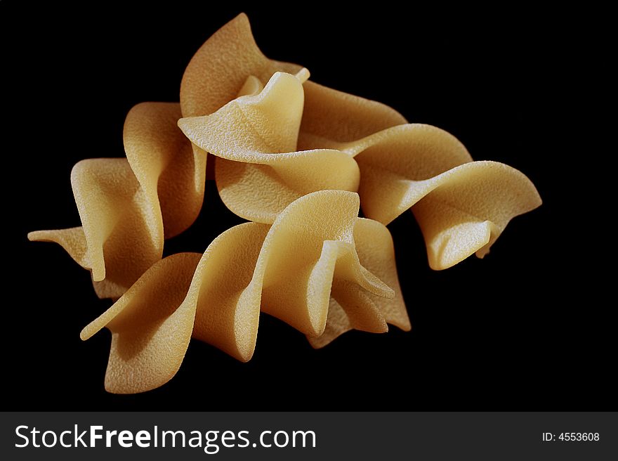 Yellow rolled pasta on black background