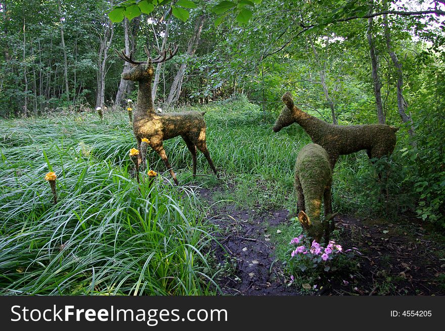 Three life like deer sculptures in a garden. Three life like deer sculptures in a garden.