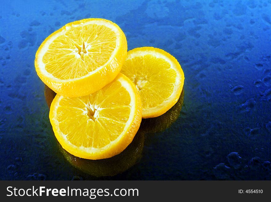 Slices of an orange on blue background with water drops