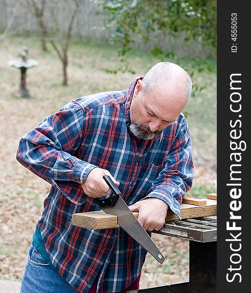 Man using hand saw to cut board. Man using hand saw to cut board